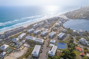 Vue aérienne d’une station balnéaire comprenant plusieurs bâtiments, une plage et une vaste étendue d’eau.