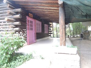 A wooden cabin with a covered porch, pink doors, and a sign above the entrance. - San Francisco Cabins 1 (Las Vegas)