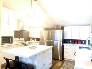 A modern kitchen with white cabinets, stainless steel appliances, and a central island.