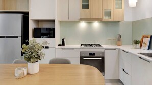 Une cuisine moderne avec des meubles blancs, un réfrigérateur en acier inoxydable, une cuisinière à gaz et un lave-vaisselle.