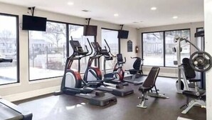 Un gimnasio con cintas de correr, una bicicleta estática y un banco de pesas.