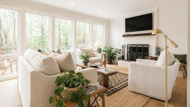 Un salón espacioso con chimenea, ventanas grandes y un televisor de pantalla plana.