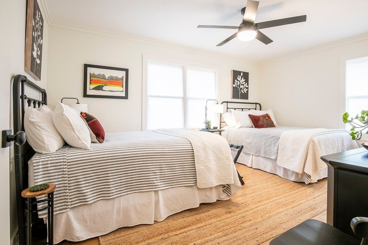 A bedroom with two beds, a ceiling fan, and a window.