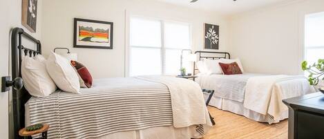 A bedroom with two beds, a ceiling fan, and a window.