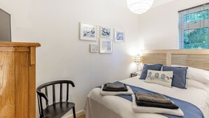 A bedroom with a bed, a desk, a chair, and wall art. - Valley Lodge - UK49228 (Gunnislake)