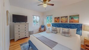 A bedroom with a bed, a dresser, a television, a ceiling fan, and artwork on the wall. - Stylish 2bd/1ba + Office & Yard (Albuquerque)