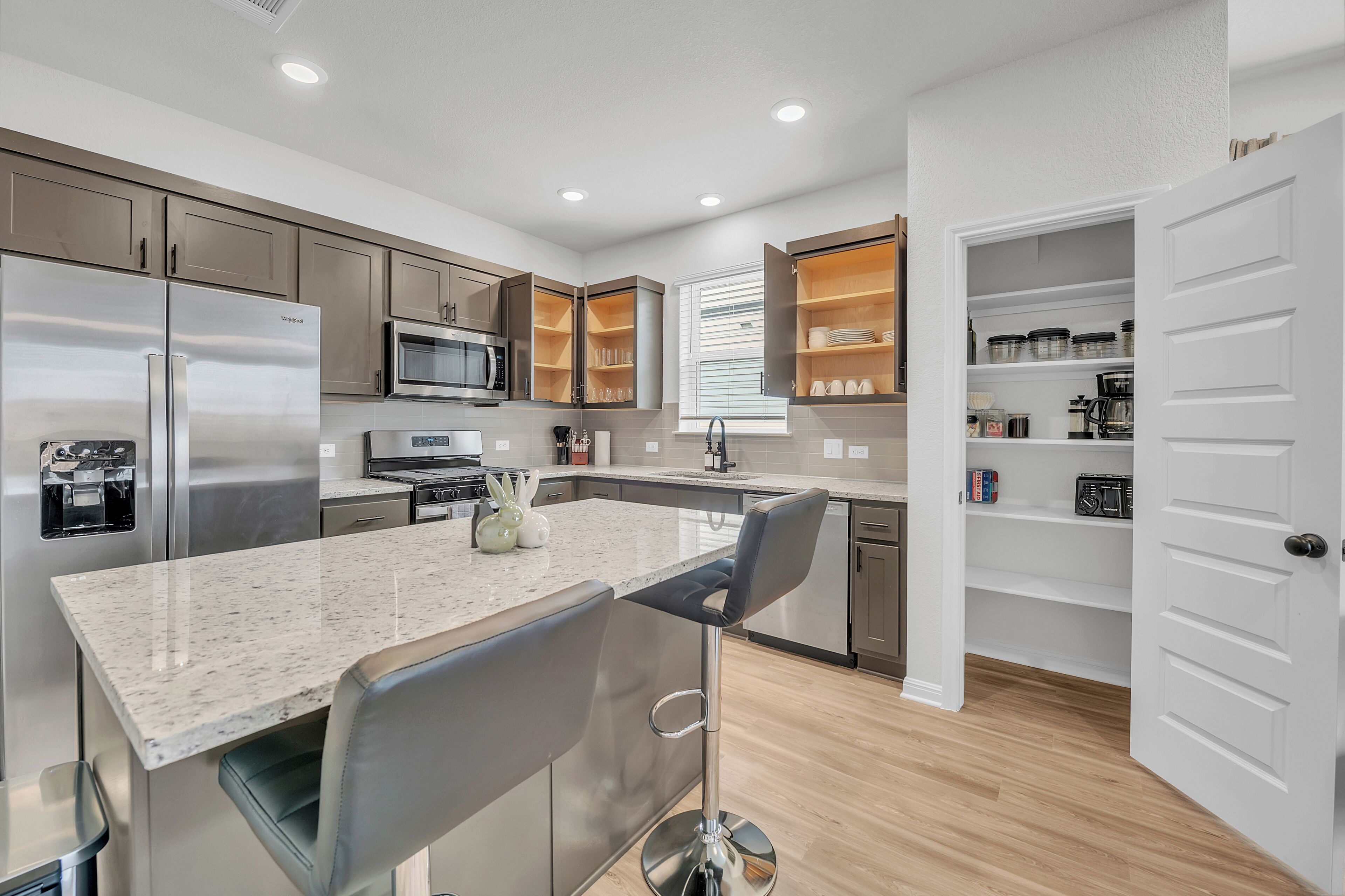A modern kitchen with stainless steel appliances, a granite countertop, and a bar stool.