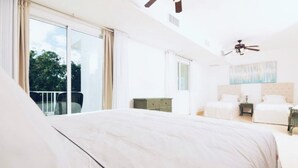 A spacious bedroom with a large bed, a ceiling fan, and a view of the outdoors through a sliding glass door. - Blue Green (Sosúa)