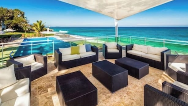 A sunlit outdoor lounge area with a pool and ocean view, furnished with sofas and chairs. - Blue Green (Sosúa)