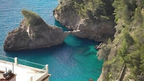 A coastal landscape with rocky formations and clear blue water.