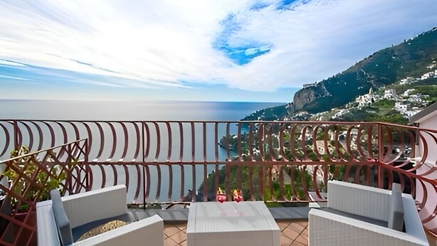 A balcony with a view of the sea and a mountainous landscape.