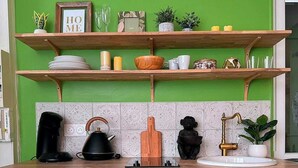 Una cocina con paredes verdes, estantes de madera y un refrigerador antiguo.