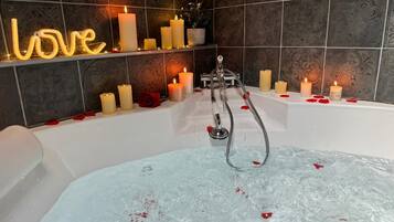 Un baño con bañera, varias velas y un letrero de neón que dice 'love'.