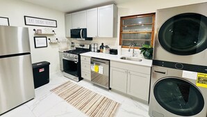 A compact kitchen with a refrigerator, stove, microwave, dishwasher, and double washing machine.