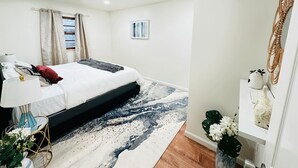 A modern bedroom with a bed, bedside table, lamp, and decorative items.