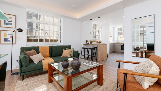 A spacious living room with a green sofa, a glass coffee table, and a brown armchair. There is a kitchen area with a bar and stools in the background. - Skandiloft - Holiday rental Malaga city (Málaga)