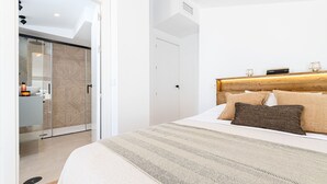 A modern bedroom with a large bed, a wooden headboard, and a glass shower enclosure. - Skandiloft - Holiday rental Malaga city (Málaga)