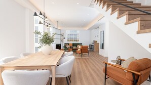 A modern interior with a wooden dining table, white chairs, a sofa, and a staircase. - Skandiloft - Holiday rental Malaga city (Málaga)