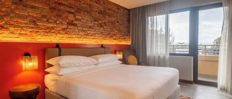 Habitación de hotel con pared de ladrillo, una cama grande, una mesita de noche y vistas al exterior.