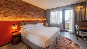 Habitación de hotel con pared de ladrillo, una cama grande, un comedor y vistas por la ventana.