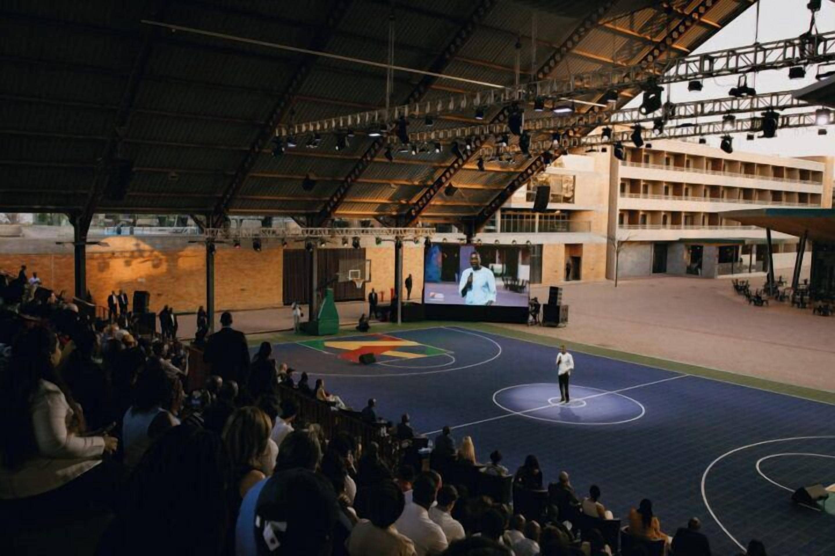 Una palestra al coperto con un vasto pubblico che assiste a una presentazione.