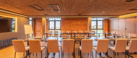 A conference room with a long table, multiple chairs, and a brick wall.