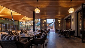 An indoor dining area with wicker chairs and tables, wooden ceiling, and pendant lighting. - Zaria Court Kigali, Tapestry Collection by Hilton (Kigali)