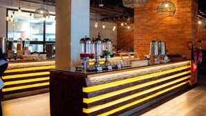 A modern bar area with a central counter, hanging pendant lights, and a brick wall backdrop. - Zaria Court Kigali, Tapestry Collection by Hilton (Kigali)