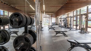 Un gimnasio con equipo de levantamiento de pesas, bancos y un espacio amplio.