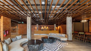 A modern lobby with a curved sofa, round coffee tables, and a patterned rug. - Zaria Court Kigali, Tapestry Collection by Hilton (Kigali)
