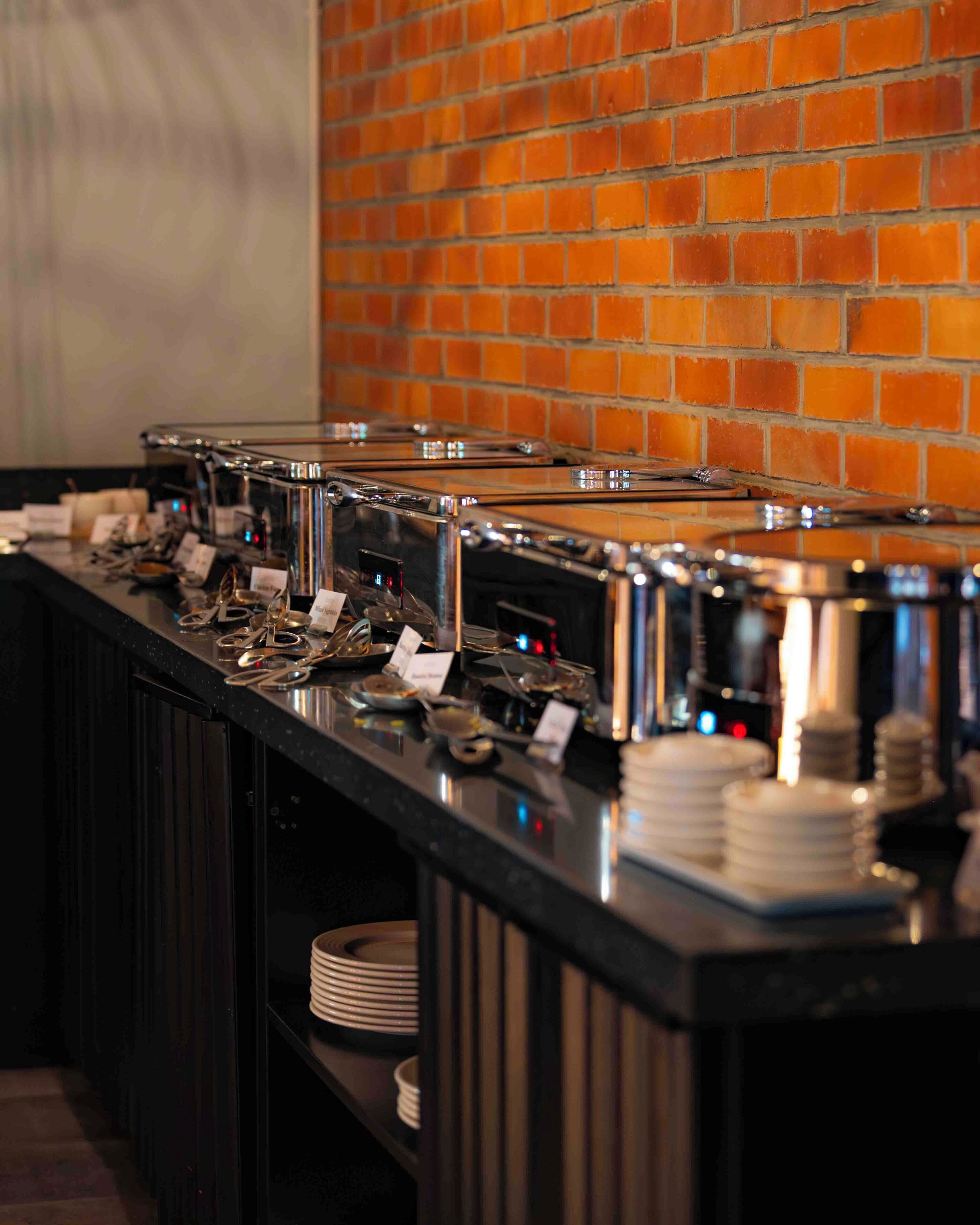 Un buffet proposant plusieurs stations en libre-service, chacune équipée d’un distributeur de plats chauds et d  ’une variété d’ustensiles.