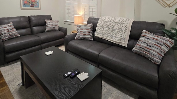 A living room with two dark leather sofas, a black coffee table, and a framed picture on the wall.