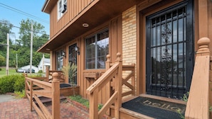 A wooden building with a porch, a black metal gate, and a brick pathway leading to the entrance.