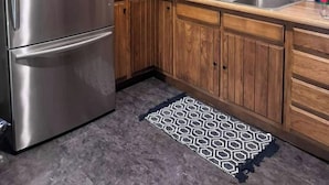 A kitchen with wooden cabinets, a stainless steel refrigerator, a sink, and a window with blinds.