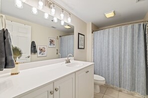 A bathroom with a white vanity, a large mirror, and a shower curtain. - Crane's Landing - Riverfront (Wilmington)