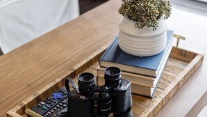 A wooden tray on a table with a camera and books.