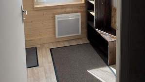 Ein Zimmer mit Fenster, Holzwänden, einer Heizung und einer dunklen Holzbank.