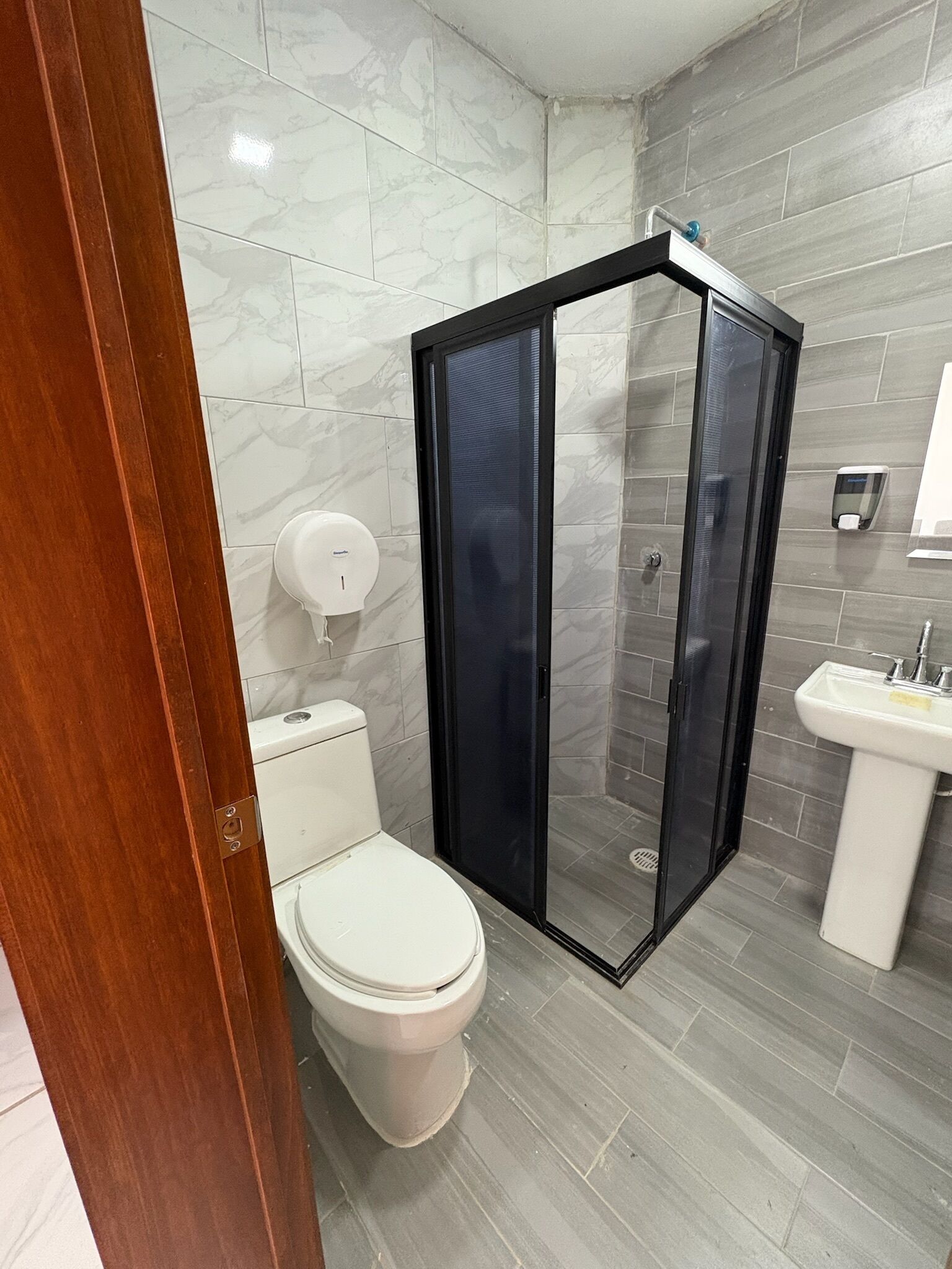 Un baño con inodoro, cabina de ducha y lavabo.