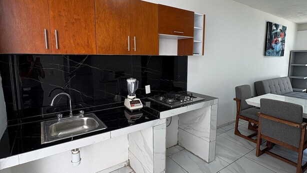A modern kitchen with black countertops, white cabinets, and a built-in stove. - Residencial Gran Cobae Dúplex A (Tonalá)