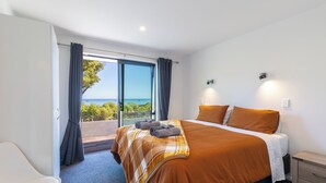 A bedroom with a large bed, a view of the sea, and a balcony. - Glass Horizon - Rutherglen Holiday Home (Ruthherglen)