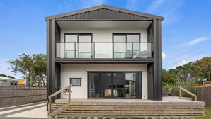 A modern two-story house with a balcony and a deck.