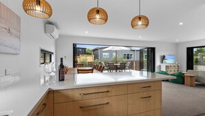 A modern kitchen with a large island, wooden cabinets, and pendant lighting.