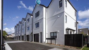 A row of modern, white apartment buildings with multiple windows and a gated entrance. - Modern Central Apartment - Christchurch Apartment (Christchurch)