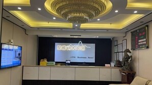 A reception area with a chandelier, a television, a reception desk, and a sofa. - Juya Business Hotel (Shanghai)