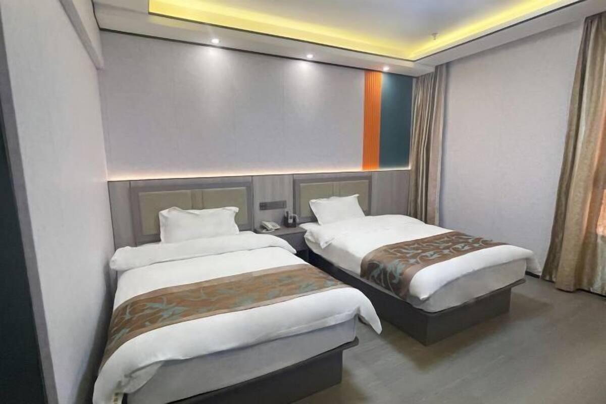 A hotel room with two beds, a nightstand, and a modern ceiling design.