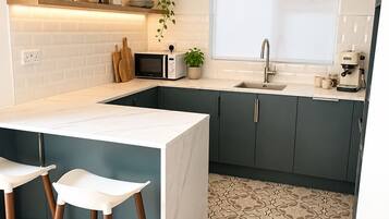 A modern kitchen with a white island, dark cabinets, and a patterned floor.