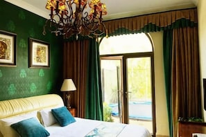 Een hotelkamer met een bed, een kroonluchter, een raam met gordijnen en uitzicht op de omgeving.