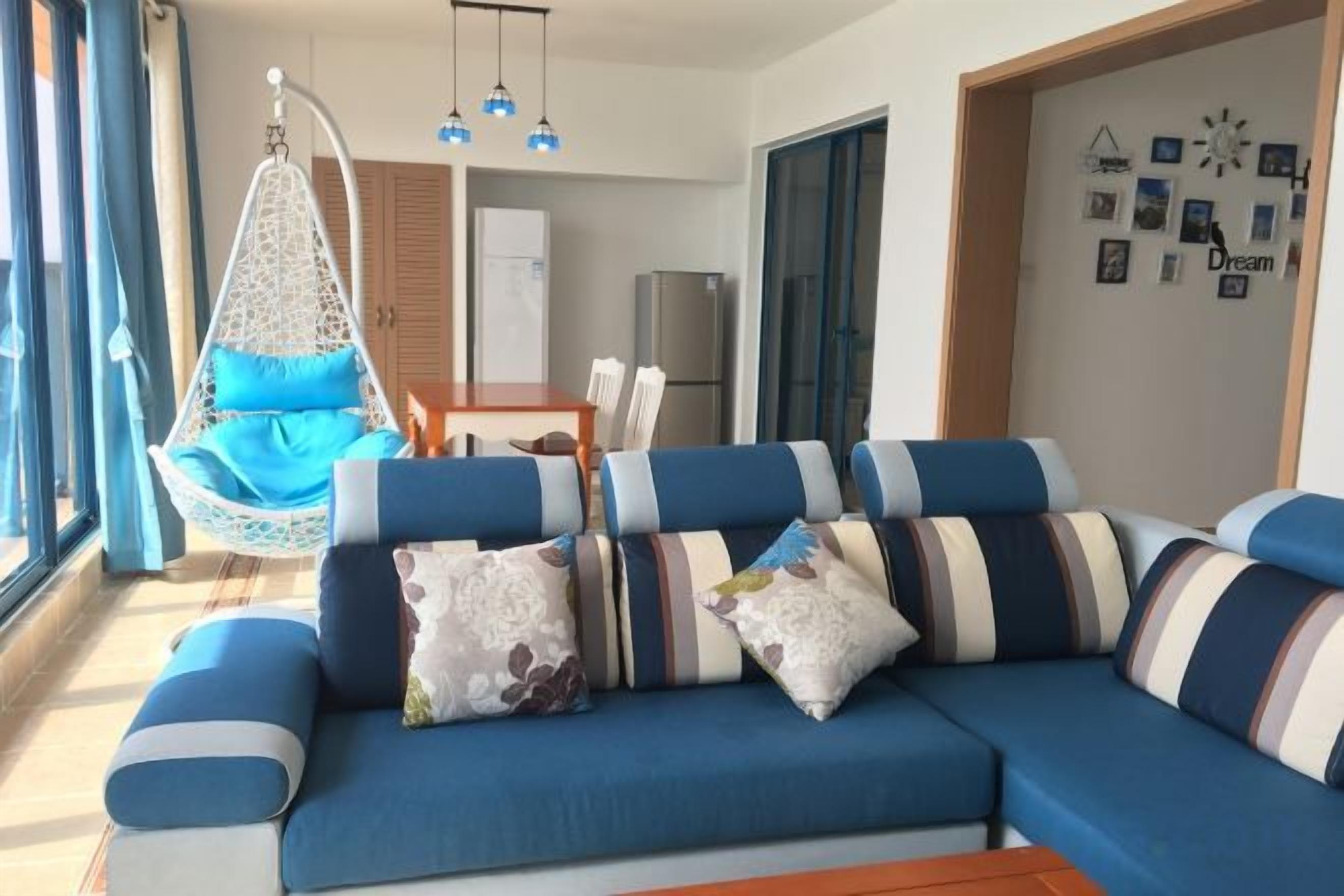 Una sala moderna con un sofá azul, un sillón colgante y un comedor.