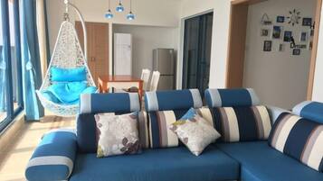Una sala moderna con un sofá azul, un sillón colgante y un comedor.