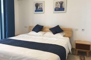 Una cama bien hecha con cabecera de madera, una mesita de noche y dos cuadros enmarcados en la pared.